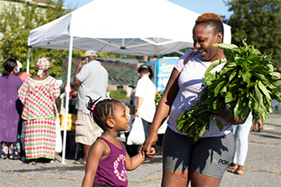 Mother and Daughter Buying Green Vegetables at a Farmer's Market