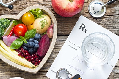 Fruits in a Bowl next to Dumbbells and a Prescription