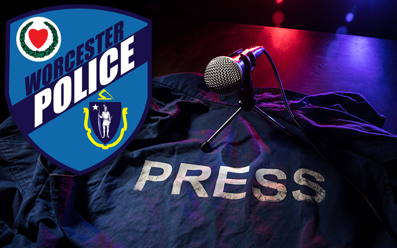 WPD Police Patch Image Over Blue Press Vest on Table with Microphone and Red and Blue Lights