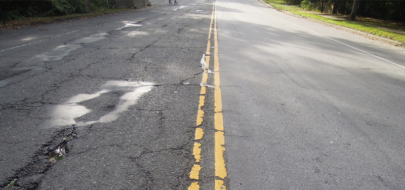Street with Yellow Lines in Center and Cracks in Pavement