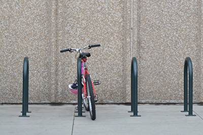 Series of Inverted U Bike Racks with Red Bike Parked at One in Front of Concrete Building
