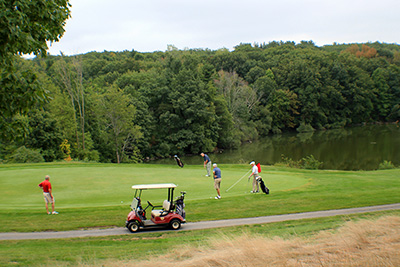 Golf Cart and Four Golfers in Front of the Pond at Green Hill Golf Course