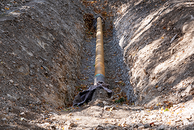 Water Pipe Exposed in Trench Dug Out in Ground