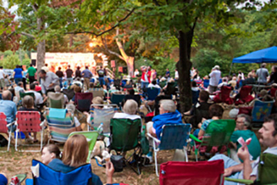 Crowd of People Sitting on Chairs and Blankets Watching an Outdoor Movie